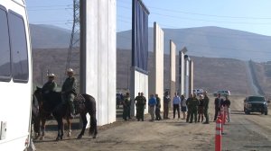 Officials stand near eight prototypes for a wall to divide the border between the U.S. and Mexico and they are unveiled on Oct. 26, 2017. (Credit: KSWB)