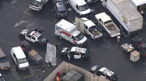 An officer raises a firearm at a stolen U-Haul as its driver tries to escape police after stopping at a produce market in downtown L.A. on Nov. 9, 2017. (Credit: KTLA)