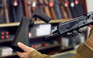 A bump stock device (left), is shown next to a AK-47 semi-automatic rifle (right). (Credit: George Frey/Getty Images)