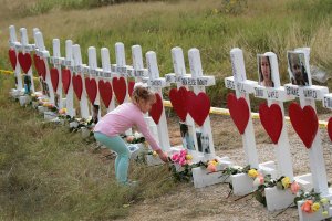 Four-year-old Shaelyn Gisler leaves a flower at a memorial where 26 crosses were placed to honor the 26 victims killed at the First Baptist Church of Sutherland Springs, Nov. 9, 2017, in Sutherland Springs, Texas. (Credit: Scott Olson / Getty Images)