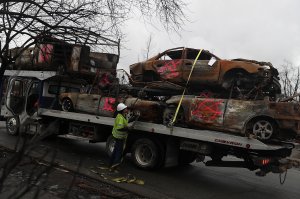 A worker secures burned-out cars onto a truck in the Coffey Park neighborhood of Santa Rosa on Nov. 13, 2017. (Credit: Justin Sullivan / Getty Images)