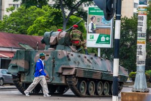 A man walks past an armoured personnel carrier that stations by an intersection as Zimbabwean soldiers regulate traffic in Harare on Nov. 15, 2017. (Credit: AFP / Getty Images)