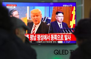 People watch a television news screen showing pictures of U.S. President Donald Trump and North Korean leader Kim Jong-Un at a railway station in Seoul on Nov. 29, 2017. (Credit: JUNG YEON-JE/AFP/Getty Images)