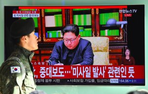 A South Korean soldier walks past a television news screen showing North Korean leader Kim Jong-Un approving the country's new ICBM test, at a railway station in Seoul on November 29, 2017. (Credit: JUNG YEON-JE/AFP/Getty Images)
