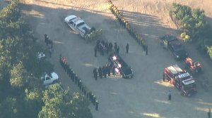 The body of a Cal Fire engineer killed while battling the Thomas Fire is loaded into the back of a hearse near Fillmore on Dec. 14, 2017. (Credit: KTLA)