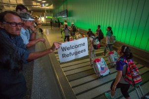 John Wider carries a welcome sign near arriving international travelers on the first day of the the partial reinstatement of the Trump travel ban, temporarily barring travelers from six Muslim-majority nations from entering the U.S., at Los Angeles International Airport (LAX) on June 29, 2017, in Los Angeles. (Credit: David McNew/Getty Images)