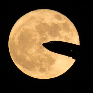 In this handout provided by NASA, an aircraft taking off from Ronald Reagan National Airport is seen passing in front of the moon as it rises on December 3, 2017 in Washington, DC. (Credit: NASA/Bill Ingalls via Getty Images)