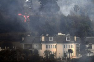 Flames are seen behind a Bel Air mansion threatened by the Skirball Fire on Dec. 6, 2017. (Credit: AFP PHOTO / Robyn Beck)