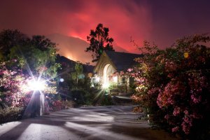 The Thomas Fire burns behind houses in Ojai on Dec. 7, 2017. (Credit: AFP PHOTO / Kyle Grillot)