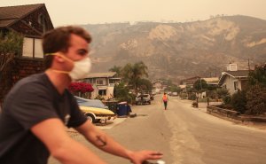 A man bicycles past bluffs burned in the Thomas Fire on Dec. 7, 2017, in La Conchita. (Credit: Mario Tama/Getty Images)