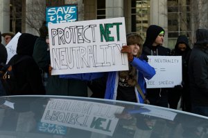 A demonstrator holds a 'Protect Net Neutrality' protest sign during a demonstration against the proposed repeal of net neutrality outside the Federal Communications Commission headquarters in Washington, DC on December 13, 2017. (Credit: ALEX EDELMAN/AFP/Getty Images)