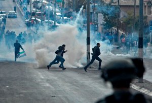 Palestinian protestors take cover from tear gas during clashes with Israeli forces following a demonstration in Bethlehem in the Israeli-occupied West Bank on Dec. 15, 2017. (Credit: MUSA AL SHAER/AFP/Getty Images)