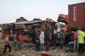 People look at the wreckage of a bus and a lorry that crashed in a head-on collision, killing thirty people near Nakuru, Kenya, on Dec. 31, 2017. (Credit: STR/AFP/Getty Images)