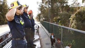 Burbank firefighters including Rich Dunn, left, salute from an overpass in Burbank as a procession for Cal Fire Engineer Cory Iverson, 32, passes by enroute to San Diego on Dec. 17, 2017. (Credit: Christina House / Los Angeles Times)