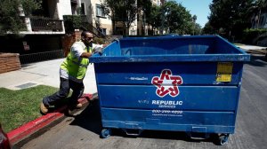 A waste collector pushes a trash bin out of a condominium complex garage in West Los Angeles. (Credit: Mel Melcon / Los Angeles Times)