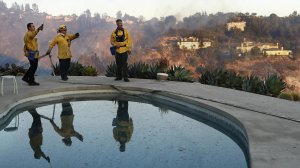 Los Angeles City firefighters Florin Sarbu, left, Dan Smithers and Robert Caropino monitor the Skirball fire from the backyard of a home on Casiano Road. (Credit: Mel Melcon / Los Angeles Times)