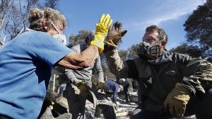 Leona Mote, left, high-fives Trevor Quirk as a team of volunteers helps sift through the rubble of her home near Ojai that burnt to the ground in the Thomas fire. Among the items recovered were her husband's wedding band, jewelry and part of a coin collection. (Credit: Mel Melcon / Los Angeles Times)