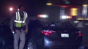An official walks past a car involved in a head-on collision involving a wrong-way driver that happened along the 210 Freeway near Lake View Terrace on Dec. 17, 2017. (Credit: KTLA)