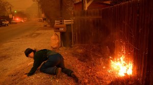 Carolyn Potter tries to save her house by putting dirt on a fire on Nye Road in Casitas Springs on Dec. 5, 2017. (Credit: Wally Skalij / Los Angeles Times)