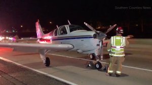 A firefighter inspects a plane that landed safely on the 55 Freeway in Costa Mesa on Jan. 28, 2018. (Credit: Southern Counties News)
