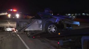 A badly-damaged vehicle involved in a wrong-way crash in Santa Ana is towed from the 55 Freeway on Jan. 5, 2018. (Credit: KTLA)