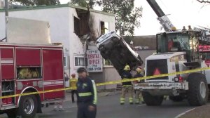Crews remove the car from the second floor of the building about 7:50 a.m. on Jan. 14, 2018. (Credit: KTLA)