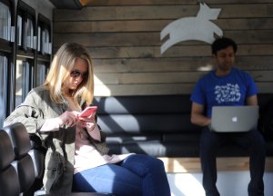 Christin Klein, left, uses her iPhone while Anindha Parthy works from his laptop on one of a luxury bus operated by Leap Transit in San Francisco on March 23, 2015. (Credit: Josh Edelson / AFP / Getty Images)