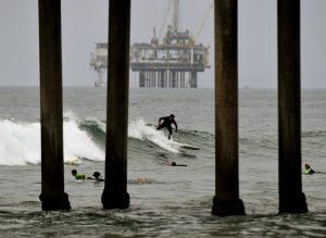 Surfers ride waves in front of an oil rig off Huntington Beach on July 31, 2015. (Credit: Mark Ralston / AFP / Getty Images)