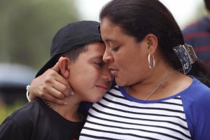 Jenny Martinez hugs her son, William Martinez, as they talk to the media about her trip from El Salvador and her need for asylum in America because of domestic violence and her fear for her life as they join with protesters in front of the United States Citizenship and Immigration Services building in Miramar, Florida, on May 19, 2017. (Credit: Joe Raedle / Getty Images)