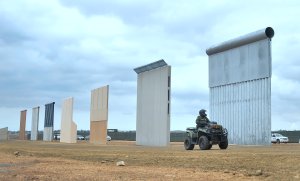 A Homeland Security border patrol officer rides an All Terrain Vehicle (ATV) past prototypes of President Donald Trump's proposed border wall on Nov. 1, 2017, in Otay Mesa. (Credit: Frederic J. Brown / AFP / Getty Images)