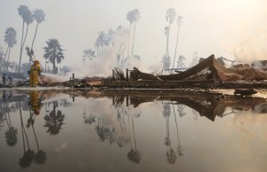 A firefighter sprays water at the remains of an apartment complex destroyed by the Thomas Fire on Dec. 5, 2017, in Ventura. (Credit: Mario Tama / Getty Images)