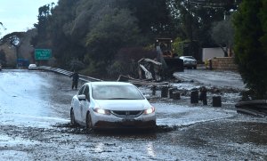A vehicle drives across a flooded US 101 freeway near the San Ysidro exit in Montecito on Jan. 9, 2018. (Credit: Frederic J. Brown/AFP/Getty Images)