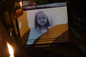 Pakistani civil society activists hold candles and placard with an image of Zainab, who was raped and murdered in the city of Kasur in Pakistan on Jan. 11, 2018 during a vigil in tribute to the child. (Credit: Aamir Qureshi / AFP / Getty Images)