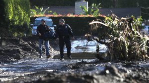A police officer escorts a resident through a neighborhood that was destroyed by a mudslide on Jan. 12, 2018, in Montecito. (Credit: Justin Sullivan/Getty Images)