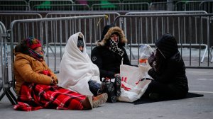 Revellers stay warm in Times Square early Sunday morning as they prepare for New Year's Eve celebrations. (Credit: Kena Betancur/AFP/Getty Images)