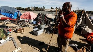Arthur Johnson looks out toward his belongings on the ground that will need to be cleaned up and stored as Orange County officials started clearing homeless camps in that area of the Santa Ana riverbed on Jan. 22, 2018. (Credit: Maria Alejandra Cardona / Los Angeles Times)