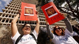 From left to right, deputy public defenders Jan Datomi and Susan Roe hold up signs protesting their new interim boss, Nichole Davis Tinkham, as they and other attorneys in the office say Tinkham is not qualified for the job. (Credit: Al Seib/Los Angeles Times)