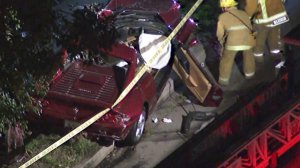 Firefighters work the scene near a Ferrari involved in a fatal crash in Pacific Palisades on Feb. 13, 2018. (Credit: KTLA)