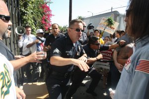 Los Angeles police officers try to clear the perimeter after angry medical marijuana advocates and protestors watched plainclothes federal Drug Enforcement Administration (DEA) agents tackle and arrest a protestor during a DEA raid of a Los Angeles medical marijuana dispensary, July 25, 2007. (Credit: Robyn Beck / AFP / Getty Images)