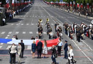 First Lady Melania Trump, President Donald Trump, French President Emmanuel Macron and his wife Brigitte Macron stand in front of the French national flag held by soldiers, at the end of the annual Bastille Day military parade on the Champs-Elysees in Paris on July 14, 2017. (Credit: ALAIN JOCARD/AFP/Getty Images)