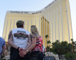 A couple stops on the Las Vegas Strip October 4, 2017, to look up at the two broken window in the Mandalay Bay hotel from which killer Stephen Paddock let loose the worst mass shooting in modern American history. (Credit: ROBYN BECK/AFP/Getty Images)