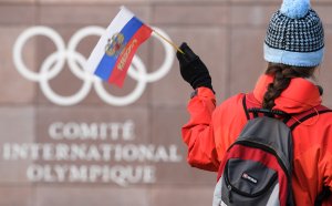 A supporter waves a Russian flag in front of the logo of the International Olympic Committee at their headquarters on Dec. 5, 2017 in Pully near Lausanne. (Credit: FABRICE COFFRINI/AFP/Getty Images)