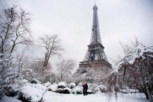 People walk through the snow covered Champ de Mars garden near the Eiffel tower on February 7, 2018 following heavy snowfall in Paris. (Credit: ALAIN JOCARD/AFP/Getty Images)