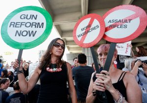 Protesters Alessandra Mondolfi (left) and Mercedes Kent (right) hold signs at a rally for gun control at the Broward County Federal Courthouse in Fort Lauderdale, on Feb. 17, 2018. (Credit: Rhona Wise/AFP/Getty Images)