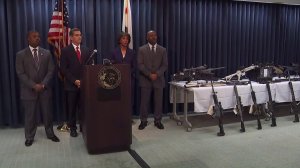 Attorney General Xavier Becerra, second from left, stands on Feb. 21, 2018, next to L.A. County District Attorney Jackie Lacey near a weapons cache seized at Steven Ponder's Temple City home. (Credit: KTLA)