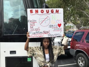 Marjory Stoneman Douglas student Tyra Hemans, 19, holds a sign as she waits for her classmates to arrive for their trip to the Capitol on Feb. 20, 2018. She said, "I'm going to Tallahassee to get justice." (Credit: Eliott C. McLaughlin/CNN)