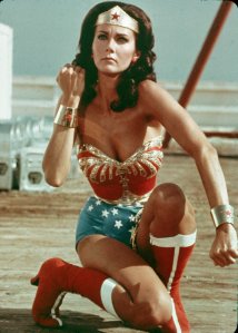 American actor Lynda Carter kneels on the ground and bears her forearm in a still from the television series Wonder Woman. (Credit: Warner Brothers/Getty Images)