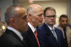 Florida Governor Rick Scott (center) stands with Andy Pollack (left) who lost his daughter Meadow Pollack, 18, and Ryan Petty who lost his daughter Alaina Petty,14, during the mass shooting at Marjory Stoneman Douglas High School, as they attend a press conference at Miami-Dade police headquarters on Feb. 27, 2018 in Doral, Florida. (Credit: Joe Raedle/Getty Images)