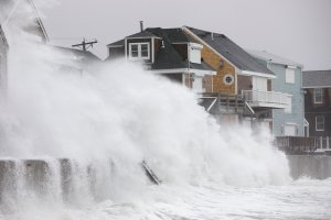 Waves crash over houses as a large coastal storm hits Scituate, Massachusetts on March 2, 2018. (Credit: Scott Eisen/Getty Images)