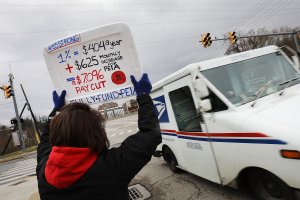 A woman holds a sign breaking down teachers' pay while supporting the statewide strike on March 2, 2018, in Morgantown, West Virginia. (Credit: Spencer Platt/Getty Images)